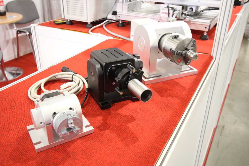 Obrotniki i uchwyty rotacyjne Mitegra prezentowane na stoisku targowym, przeznaczone do znakowania elementów cylindrycznych.